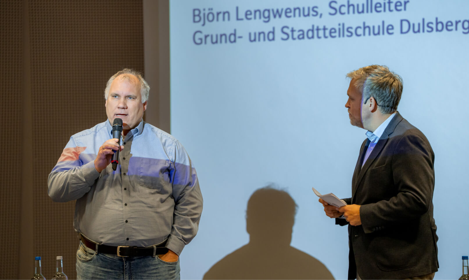 Björn Lengwenus am Mikrofon bei Bürgerdialog zum Olympia-Konzept Hamburg, Moderator steht daneben