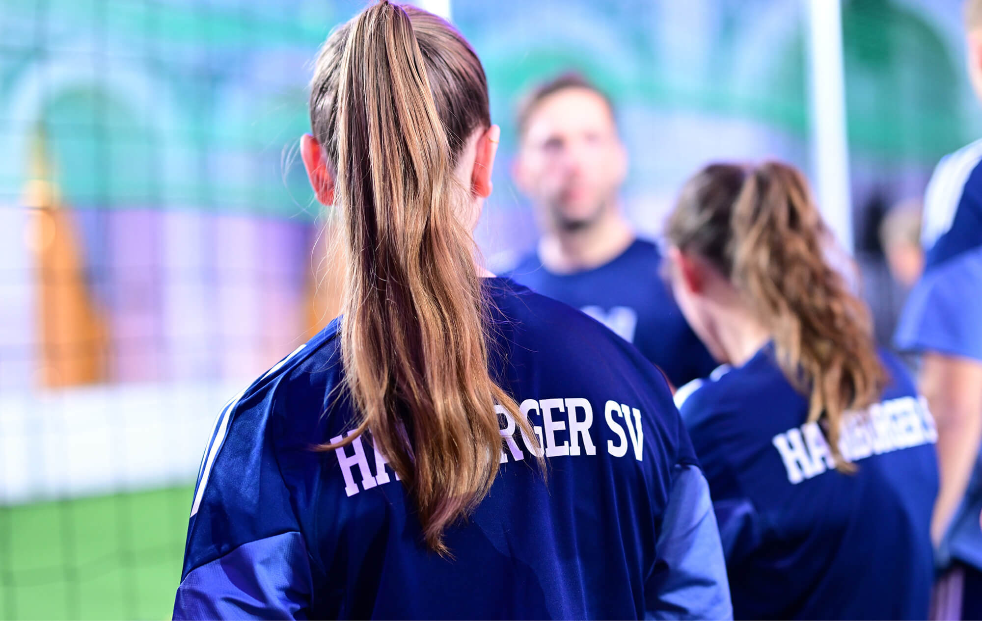 Zwei Frauen in HSV-Trainingsjacken am Spielfeldrand beim Handelskammer Cup 2025 im Börsensaal Hamburg